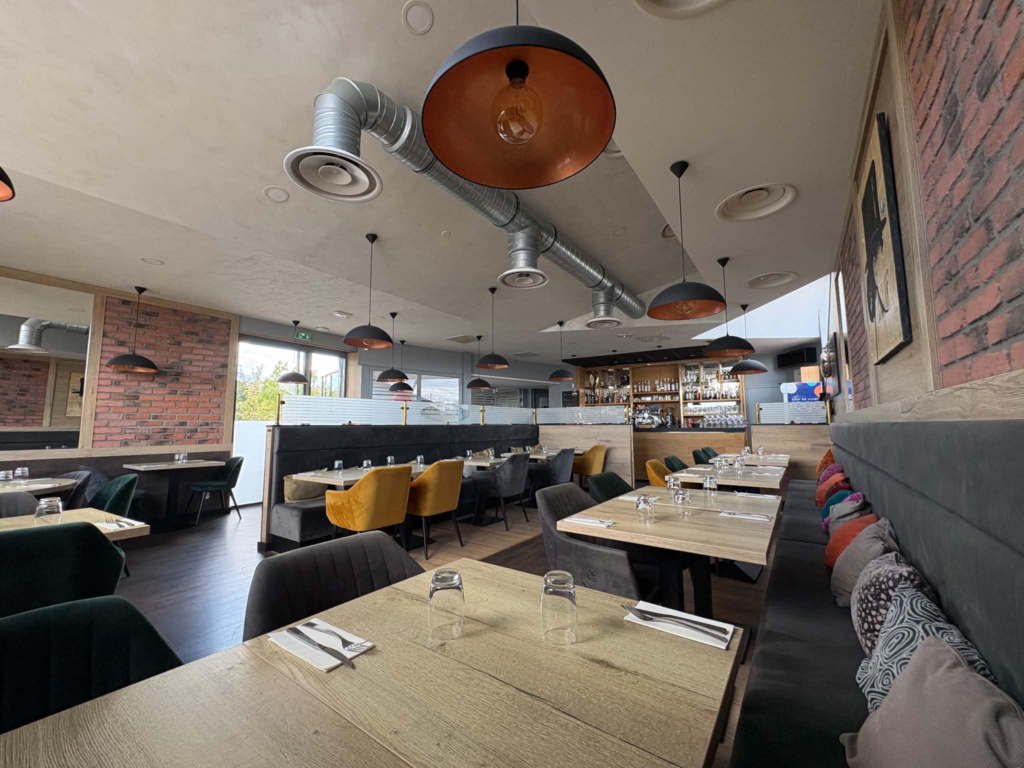 Salle principale du Restaurant L'Incontournable, éclairée à la lumière du jour.